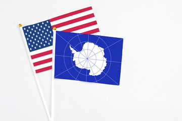 Fototapeta na wymiar Antarctica and United States stick flags on white background. High quality fabric, miniature national flag. Peaceful global concept.White floor for copy space.
