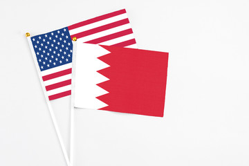 Bahrain and United States stick flags on white background. High quality fabric, miniature national flag. Peaceful global concept.White floor for copy space.