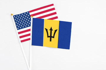 Barbados and United States stick flags on white background. High quality fabric, miniature national flag. Peaceful global concept.White floor for copy space.