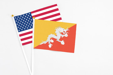 Bhutan and United States stick flags on white background. High quality fabric, miniature national flag. Peaceful global concept.White floor for copy space.