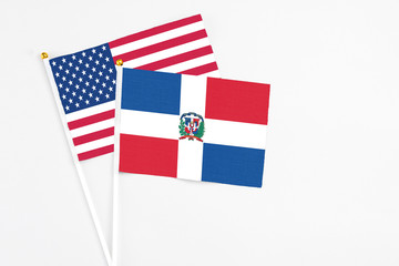 Dominican Republic and United States stick flags on white background. High quality fabric, miniature national flag. Peaceful global concept.White floor for copy space.