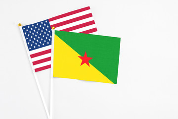 French Guiana and United States stick flags on white background. High quality fabric, miniature national flag. Peaceful global concept.White floor for copy space.