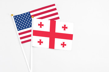 Fototapeta na wymiar Georgia and United States stick flags on white background. High quality fabric, miniature national flag. Peaceful global concept.White floor for copy space.