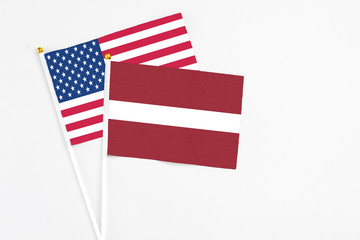 Latvia and United States stick flags on white background. High quality fabric, miniature national flag. Peaceful global concept.White floor for copy space.
