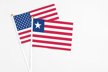 Liberia and United States stick flags on white background. High quality fabric, miniature national flag. Peaceful global concept.White floor for copy space.