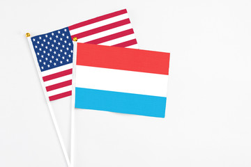 Luxembourg and United States stick flags on white background. High quality fabric, miniature national flag. Peaceful global concept.White floor for copy space.