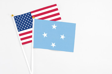 Micronesia and United States stick flags on white background. High quality fabric, miniature national flag. Peaceful global concept.White floor for copy space.