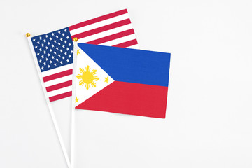 Philippines and United States stick flags on white background. High quality fabric, miniature national flag. Peaceful global concept.White floor for copy space.