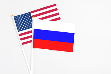 Russia and United States stick flags on white background. High quality fabric, miniature national flag. Peaceful global concept.White floor for copy space.