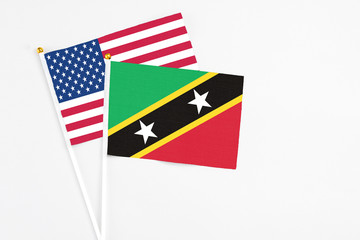 Saint Kitts And Nevis and United States stick flags on white background. High quality fabric, miniature national flag. Peaceful global concept.White floor for copy space.