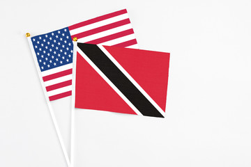 Trinidad And Tobago and United States stick flags on white background. High quality fabric, miniature national flag. Peaceful global concept.White floor for copy space.
