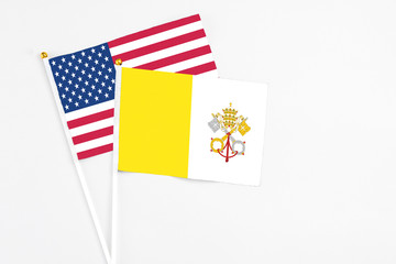 Vatican City and United States stick flags on white background. High quality fabric, miniature national flag. Peaceful global concept.White floor for copy space.