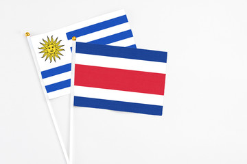 Costa Rica and Uruguay stick flags on white background. High quality fabric, miniature national flag. Peaceful global concept.White floor for copy space.