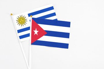 Cuba and Uruguay stick flags on white background. High quality fabric, miniature national flag. Peaceful global concept.White floor for copy space.