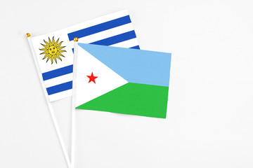 Djibouti and Uruguay stick flags on white background. High quality fabric, miniature national flag. Peaceful global concept.White floor for copy space.