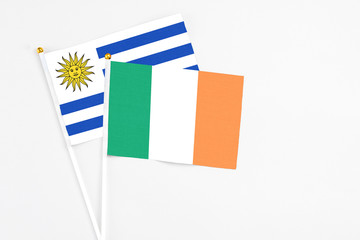 Ireland and Uruguay stick flags on white background. High quality fabric, miniature national flag. Peaceful global concept.White floor for copy space.