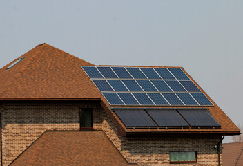 Fototapeta premium Solar panels are installed and used on the roof of a brick house.