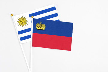 Liechtenstein and Uruguay stick flags on white background. High quality fabric, miniature national flag. Peaceful global concept.White floor for copy space.