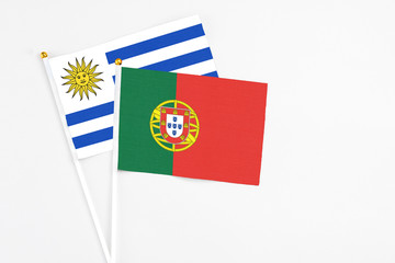 Portugal and Uruguay stick flags on white background. High quality fabric, miniature national flag. Peaceful global concept.White floor for copy space.