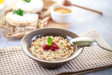 Baked granola with milk and raspberries in a plate, whole grain breads and freshly squeezed juice. A wholesome and dietary breakfast. Delicious muesli.