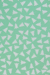 White confetti in the shape of Christmas trees on minty background. Christmas and new year concept. Trendy color of year 2020. Top view, flat lay.