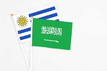 Saudi Arabia and Uruguay stick flags on white background. High quality fabric, miniature national flag. Peaceful global concept.White floor for copy space.