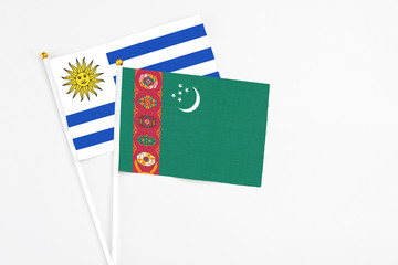 Turkmenistan and Uruguay stick flags on white background. High quality fabric, miniature national flag. Peaceful global concept.White floor for copy space.