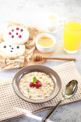 Fototapeta na wymiar Baked granola with milk and raspberries in a plate, whole grain breads and freshly squeezed juice. A wholesome and dietary breakfast. Delicious muesli