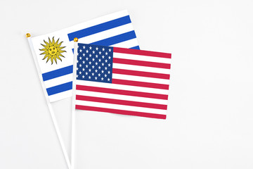 United States and Uruguay stick flags on white background. High quality fabric, miniature national flag. Peaceful global concept.White floor for copy space.