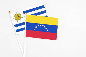 Venezuela and Uruguay stick flags on white background. High quality fabric, miniature national flag. Peaceful global concept.White floor for copy space.