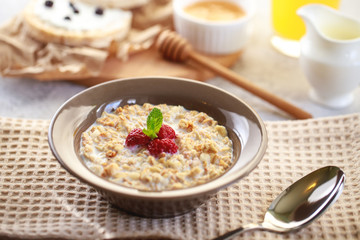 Baked granola with milk and raspberries in a plate, whole grain breads and freshly squeezed juice. A wholesome and dietary breakfast. Delicious muesli