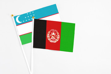 Afghanistan and Uzbekistan stick flags on white background. High quality fabric, miniature national flag. Peaceful global concept.White floor for copy space.
