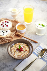Baked granola with milk and raspberries in a plate, whole grain breads and freshly squeezed juice. A wholesome and dietary breakfast. Delicious muesli