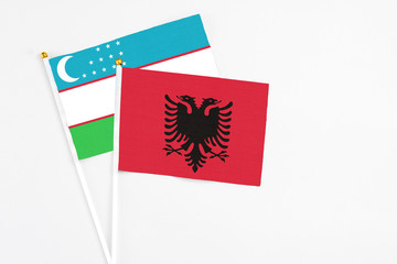 Obraz na płótnie Canvas Albania and Uzbekistan stick flags on white background. High quality fabric, miniature national flag. Peaceful global concept.White floor for copy space.