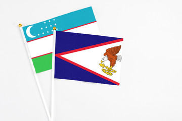 American Samoa and Uzbekistan stick flags on white background. High quality fabric, miniature national flag. Peaceful global concept.White floor for copy space.