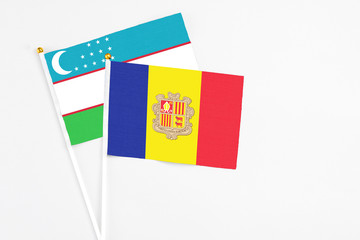 Andorra and Uzbekistan stick flags on white background. High quality fabric, miniature national flag. Peaceful global concept.White floor for copy space.