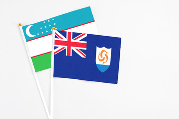 Anguilla and Uzbekistan stick flags on white background. High quality fabric, miniature national flag. Peaceful global concept.White floor for copy space.