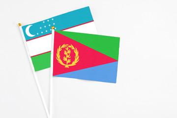 Eritrea and Uzbekistan stick flags on white background. High quality fabric, miniature national flag. Peaceful global concept.White floor for copy space.