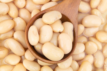 Baked white beans with wooden spoon close up