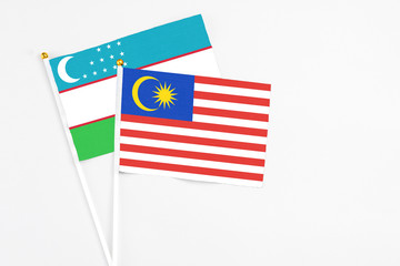 Malaysia and Uzbekistan stick flags on white background. High quality fabric, miniature national flag. Peaceful global concept.White floor for copy space.