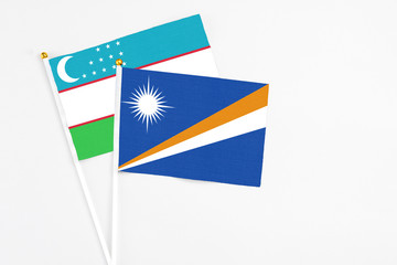 Marshall Islands and Uzbekistan stick flags on white background. High quality fabric, miniature national flag. Peaceful global concept.White floor for copy space.