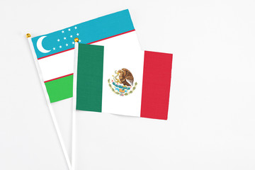 Mexico and Uzbekistan stick flags on white background. High quality fabric, miniature national flag. Peaceful global concept.White floor for copy space.