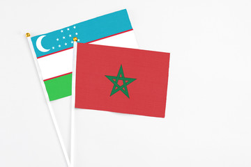 Morocco and Uzbekistan stick flags on white background. High quality fabric, miniature national flag. Peaceful global concept.White floor for copy space.