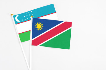 Namibia and Uzbekistan stick flags on white background. High quality fabric, miniature national flag. Peaceful global concept.White floor for copy space.