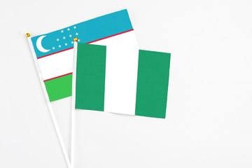 Nigeria and Uzbekistan stick flags on white background. High quality fabric, miniature national flag. Peaceful global concept.White floor for copy space.