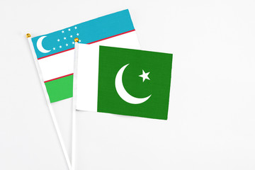 Pakistan and Uzbekistan stick flags on white background. High quality fabric, miniature national flag. Peaceful global concept.White floor for copy space.