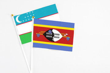 Swaziland and Uzbekistan stick flags on white background. High quality fabric, miniature national flag. Peaceful global concept.White floor for copy space.