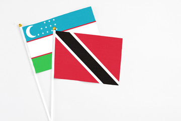 Trinidad And Tobago and Uzbekistan stick flags on white background. High quality fabric, miniature national flag. Peaceful global concept.White floor for copy space.