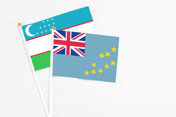 Tuvalu and Uzbekistan stick flags on white background. High quality fabric, miniature national flag. Peaceful global concept.White floor for copy space.