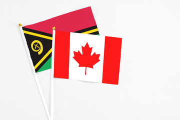Fototapeta na wymiar Canada and Vanuatu stick flags on white background. High quality fabric, miniature national flag. Peaceful global concept.White floor for copy space.